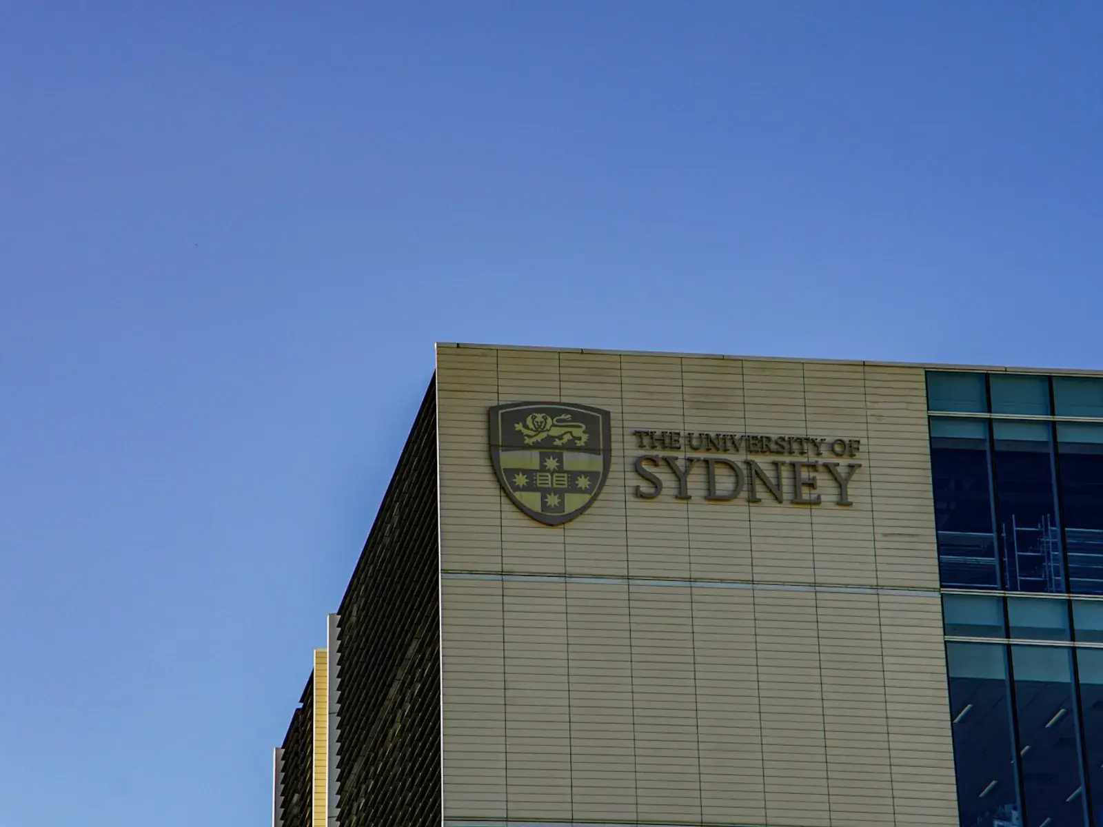A modern University of Sydney campus building under a clear blue sky