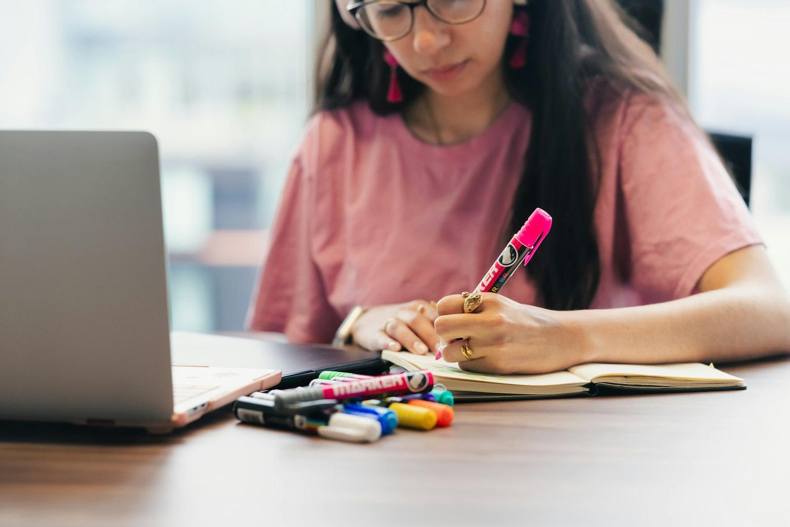 A student organizing handwritten notes beside a laptop