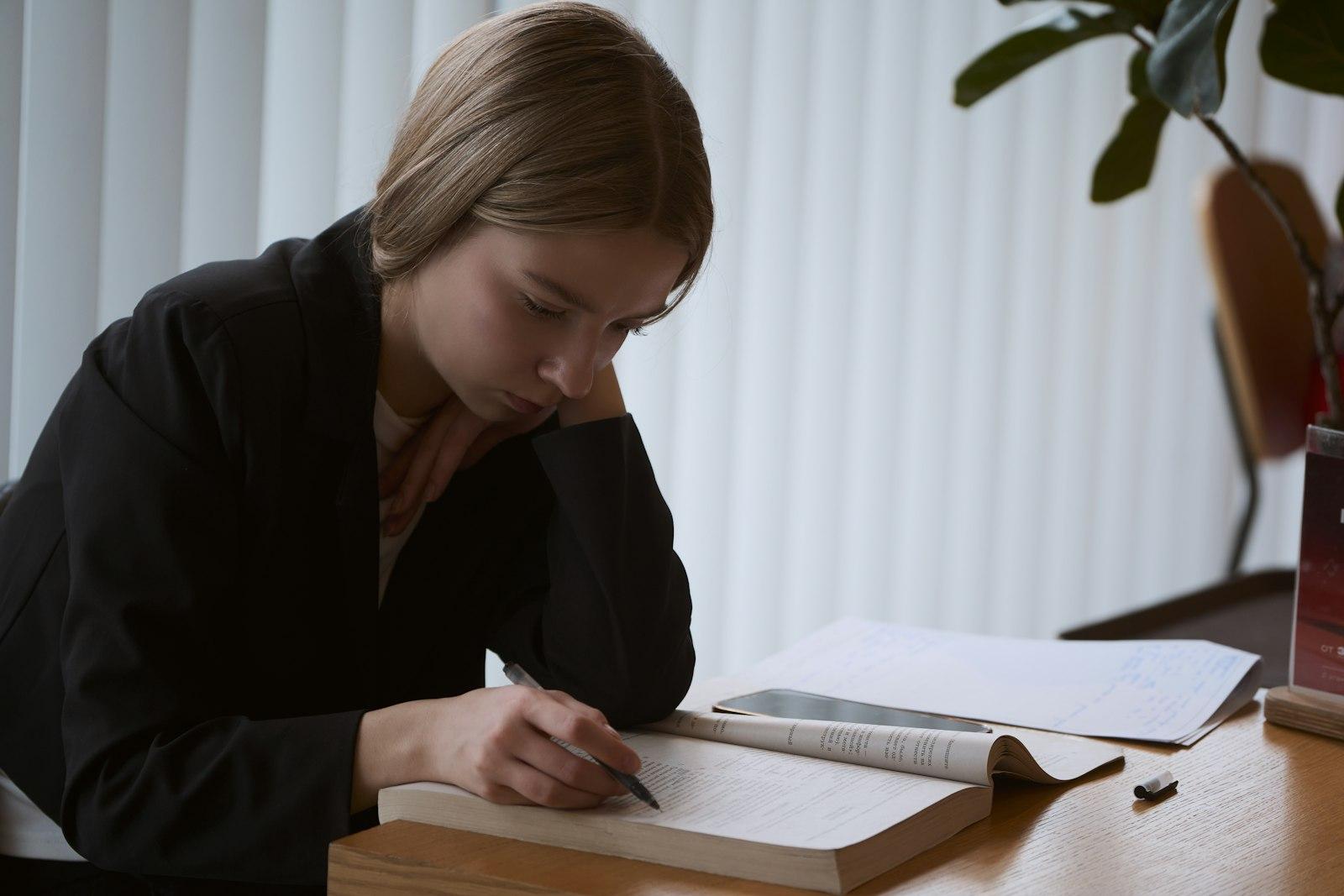 A student annotating an open book at a study desk