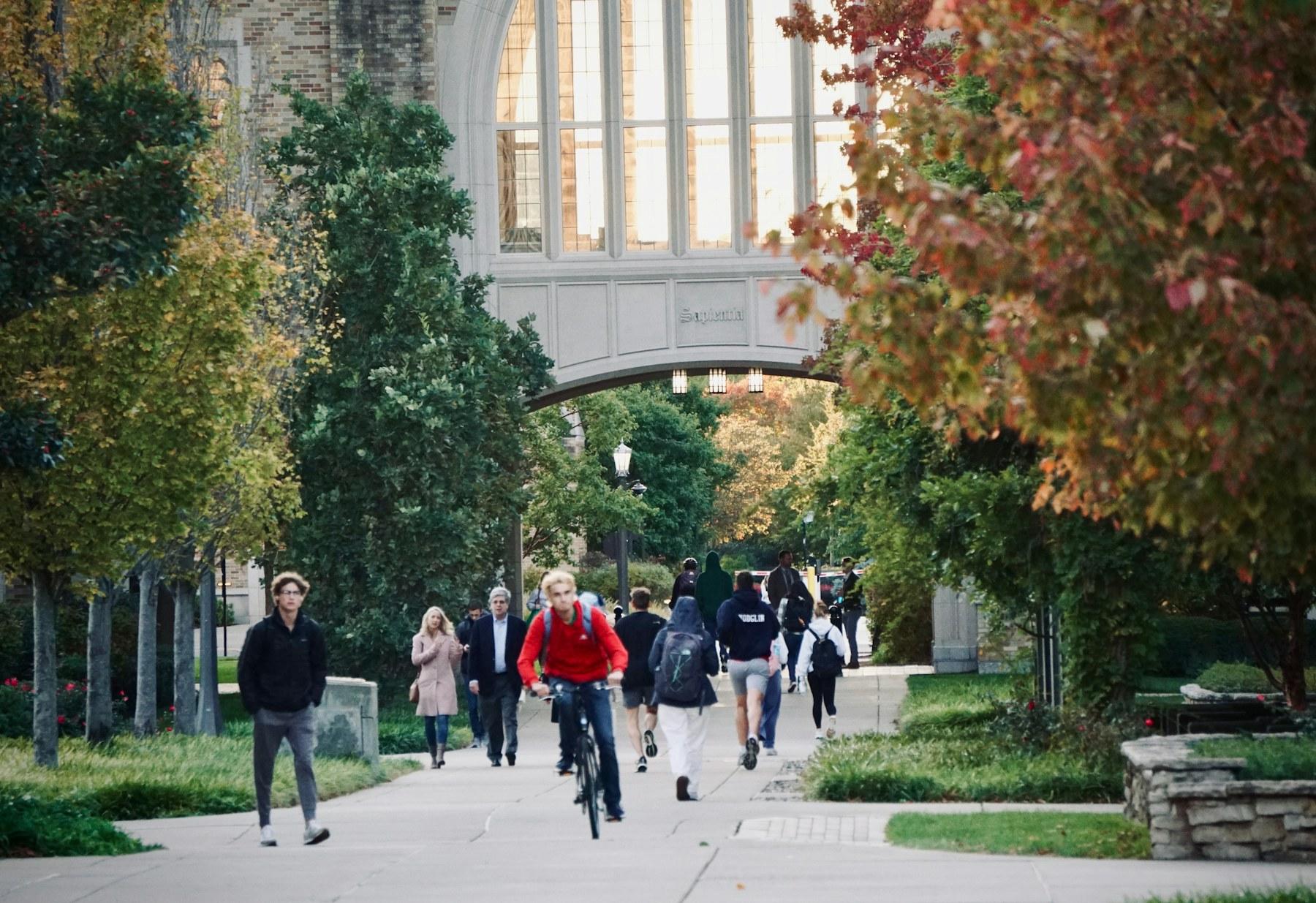 Students walking and cycling through a university campus in autumn