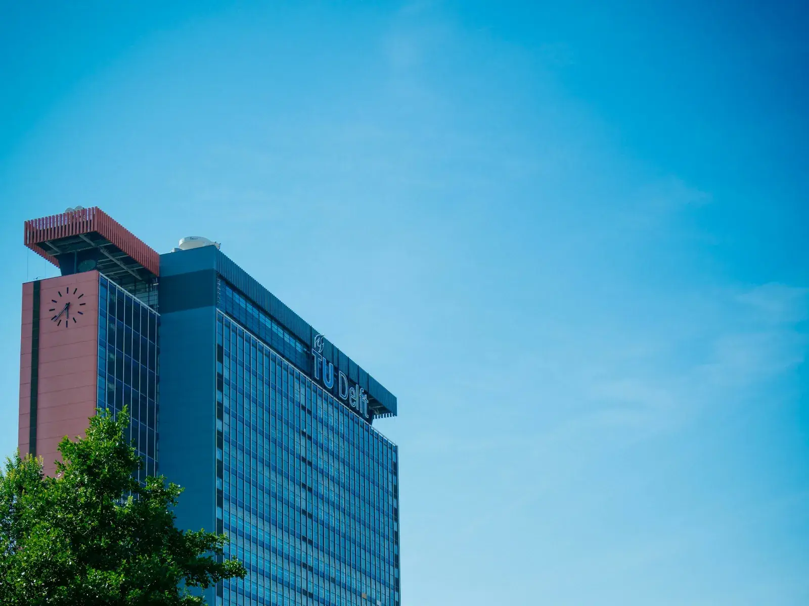 The TU Delft campus tower beside a green university lawn